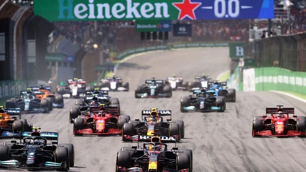 Carros da Ferrari e Mercedes disputando posição em circuito da Fórmula 1 com Red Bull ao fundo