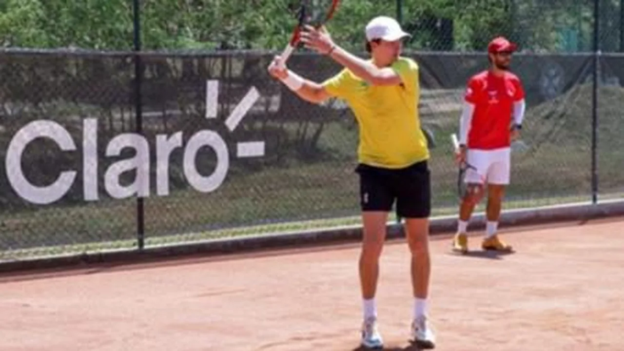 João Fonseca sacando em quadra de saibro durante partida de tênis profissional
