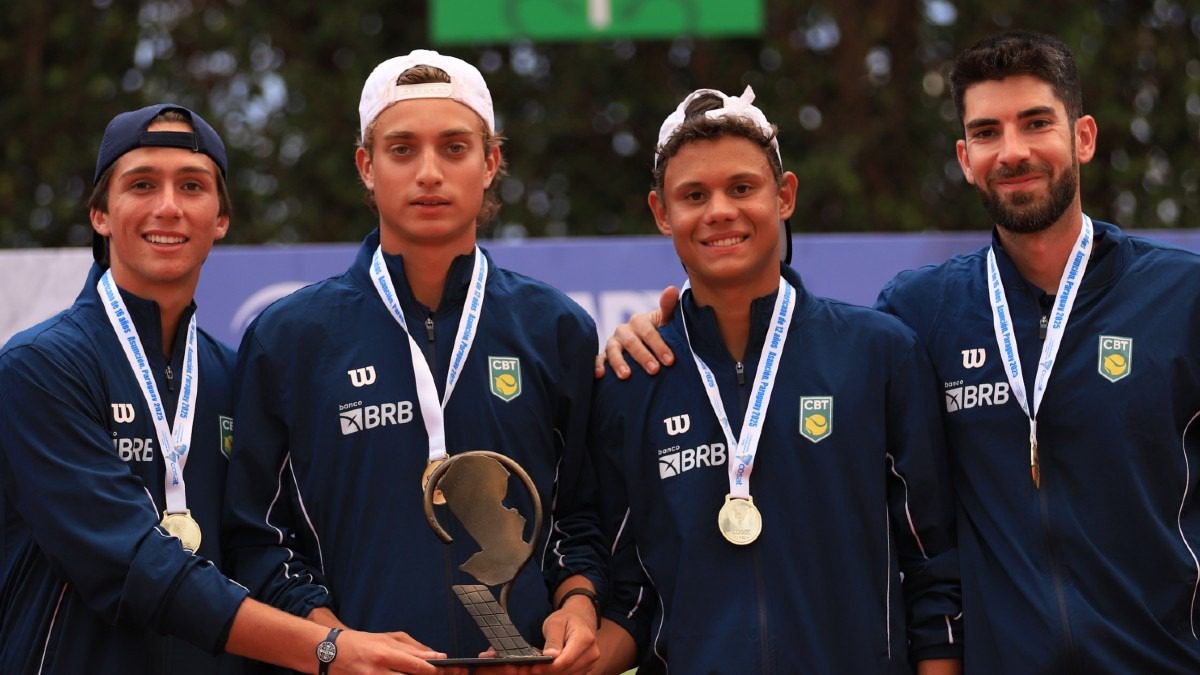 Jovens tenistas brasileiros em ação durante partida de tênis em quadra de saibro com rede e raquetes