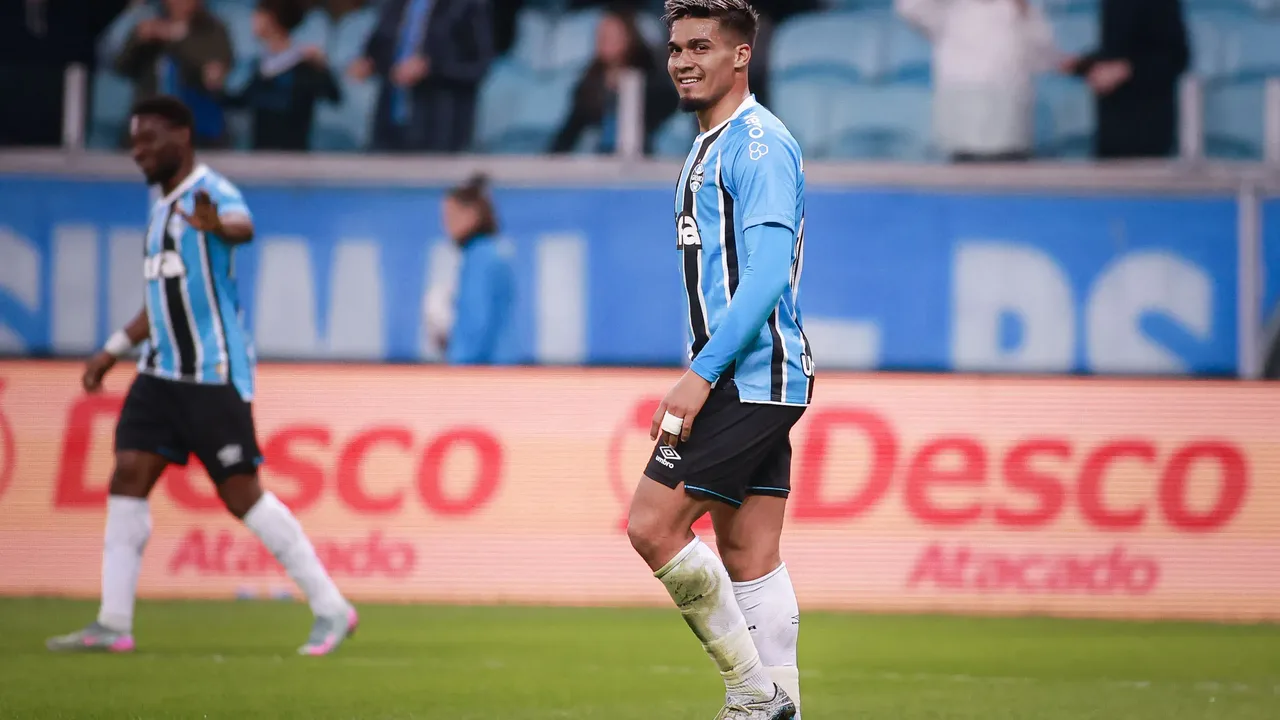 Franco Arezo em ação pelo Grêmio durante partida no estádio Arena, demonstrando técnica com a bola nos pés