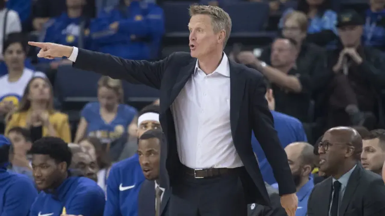 Steve Kerr pensativo durante timeout dos Golden State Warriors no Chase Center com jogadores ao fundo