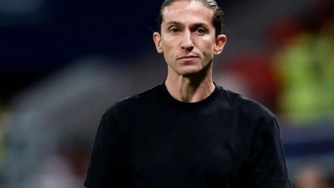 Técnico de futebol cabisbaixo no banco de reservas durante partida do Campeonato Brasileiro