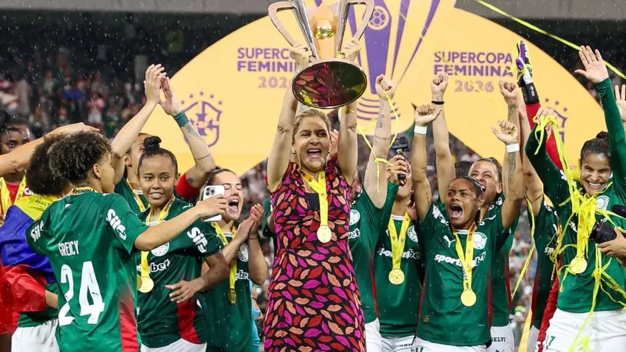 Jogadoras do Palmeiras feminino treinando em campo gramado com escudo alviverde ao fundo