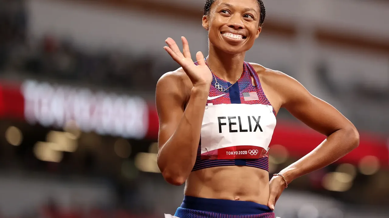 Allyson Felix cruzando a linha de chegada em pista de atletismo com bandeira americana ao fundo