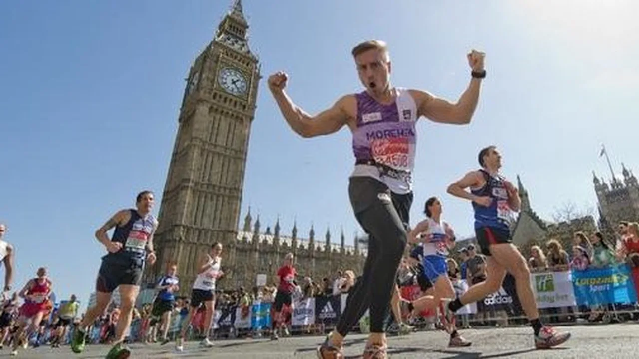 Sabastian Sawe cruzando a linha de chegada da Maratona de Londres com cronômetro marcando 1h59min30s