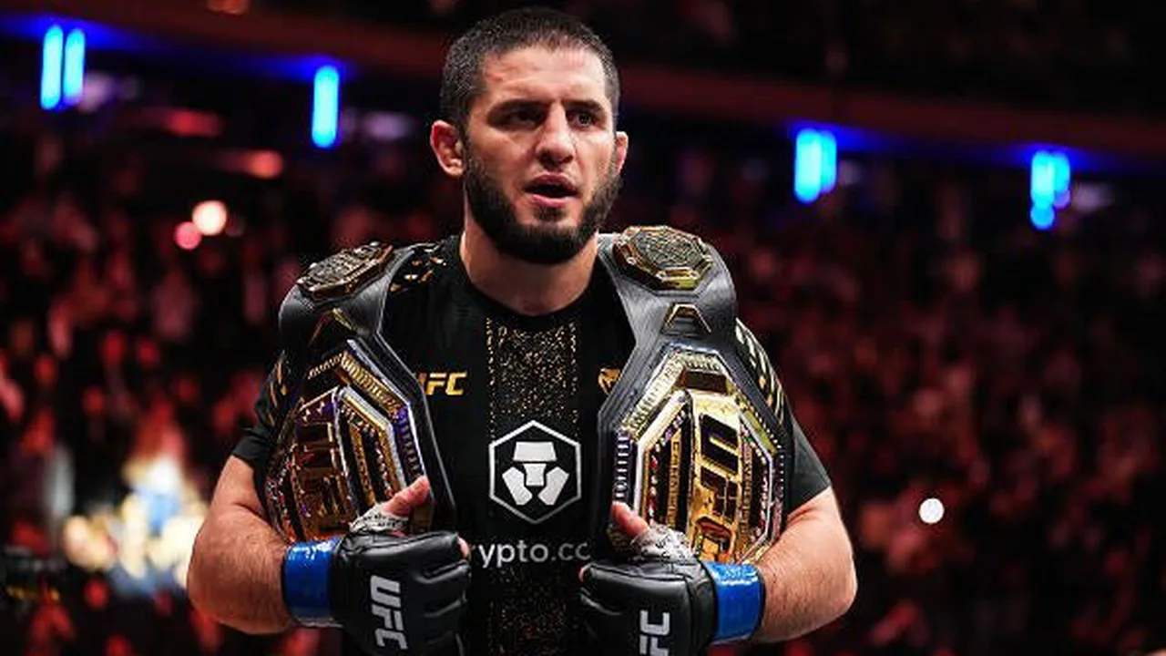 Alex Pereira com cinturão do UFC levantado após nocaute, dentro do octógono iluminado