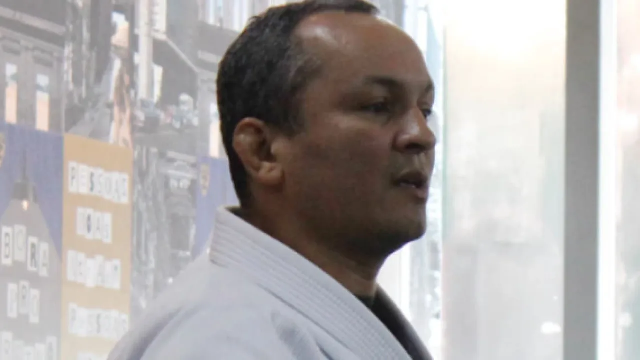 Tatame de jiu-jitsu vazio em academia com kimono e faixas coloridas ao fundo