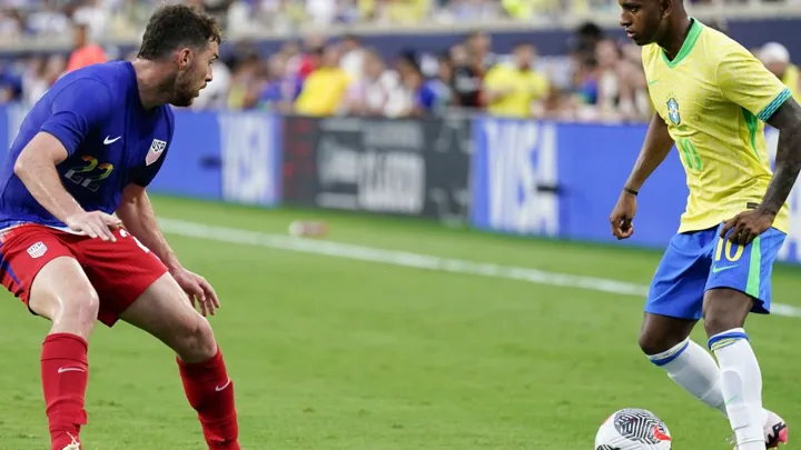 Árbitro assistente levantando a bandeira de impedimento em uma partida de futebol, com jogadores em campo