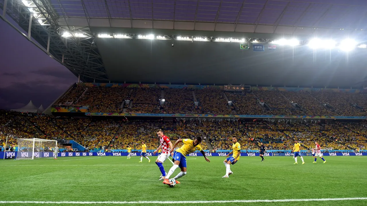Jogadores do Irã durante partida da Copa do Mundo, com bandeira iraniana ao fundo nas arquibancadas