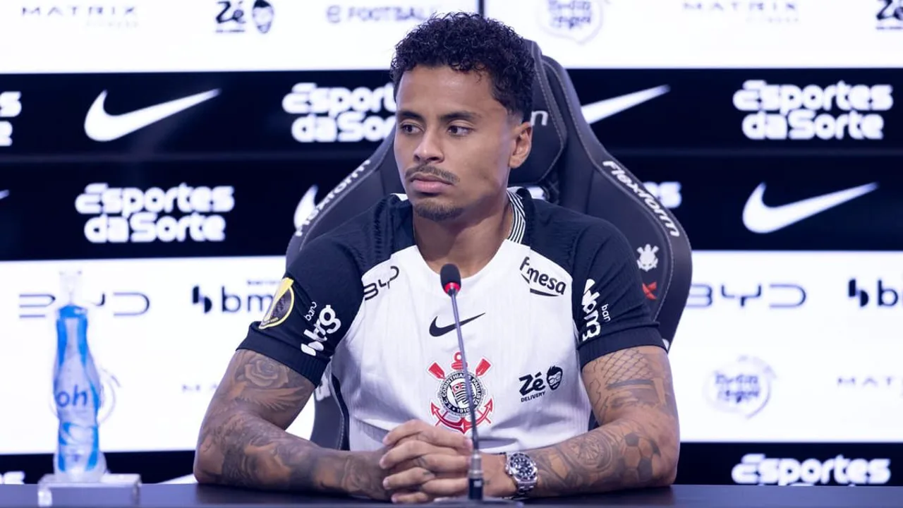 Volante Allan com a camisa do Corinthians em campo, com o Estádio El Campín ao fundo sob céu nublado de Bogotá