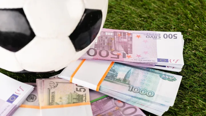 Escudo da UEFA sobre fundo com notas de euro e balanço financeiro representando o fair play financeiro