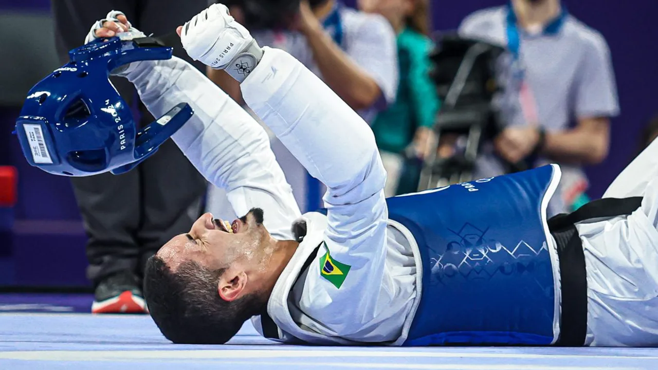 Maicon de Andrade em posição de luta no tatame olímpico, com uniforme do taekwondo brasileiro