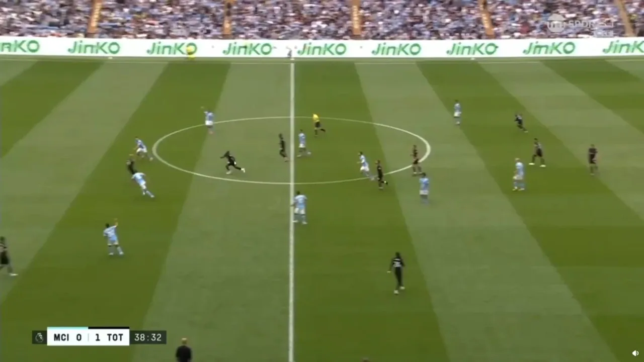 Árbitro assistente levantando a bandeira de offside em partida de futebol, com jogadores em campo ao fundo