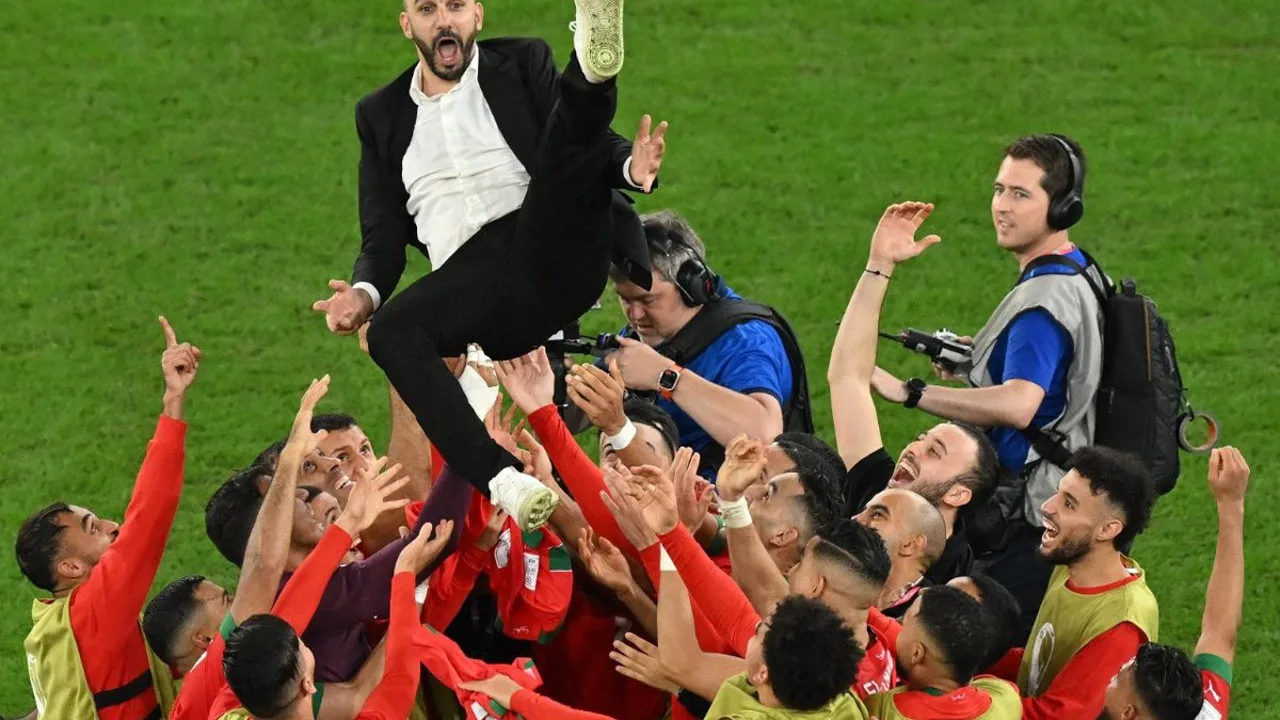 Jogadores da seleção de Marrocos celebrando gol durante partida da Copa do Mundo com bandeiras nas arquibancadas