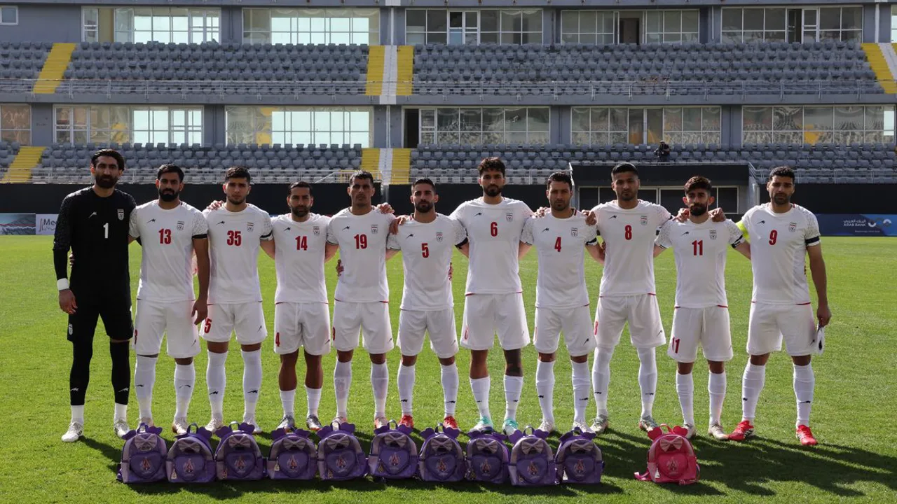 Jogadores do Irã em campo durante partida eliminatória, com bandeira da República Islâmica ao fundo nas arquibancadas