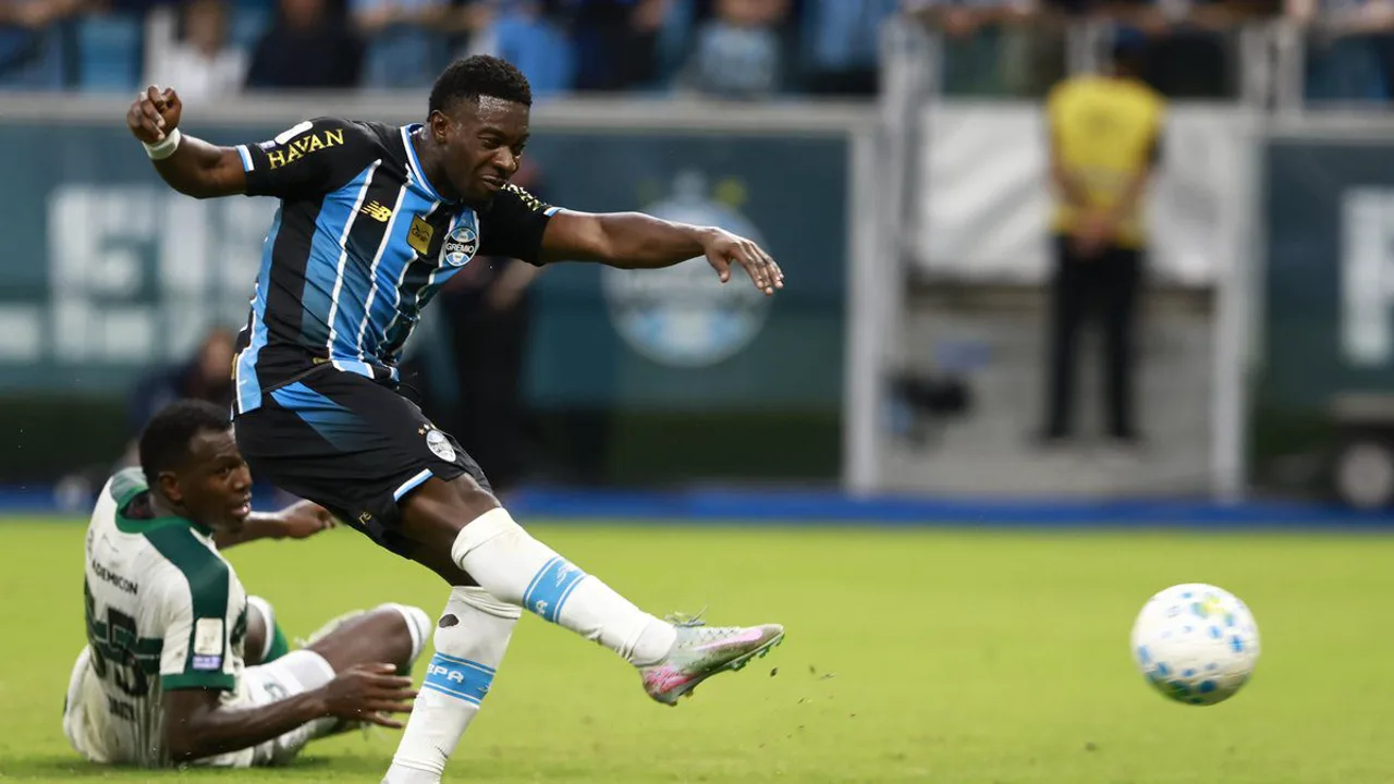 Amuzu com a camisa do Grêmio em ação durante partida na Arena, olhando para o horizonte