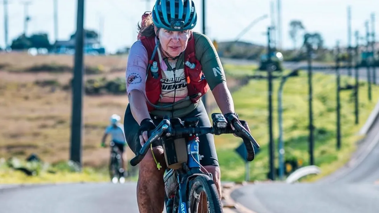 Ciclista pedalando em estrada de terra na Serra da Mantiqueira à noite, com névoa e vegetação densa ao fundo