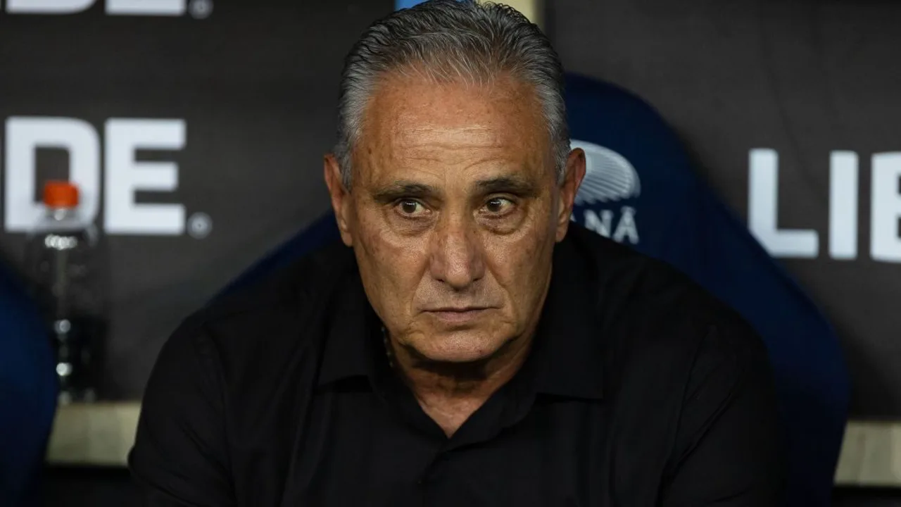 Tite de braços cruzados na beira do campo com escudo do Corinthians ao fundo