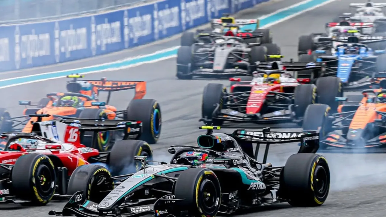 Engenheiros da F1 analisam unidade de potência em box durante corrida, com telas de telemetria ao fundo