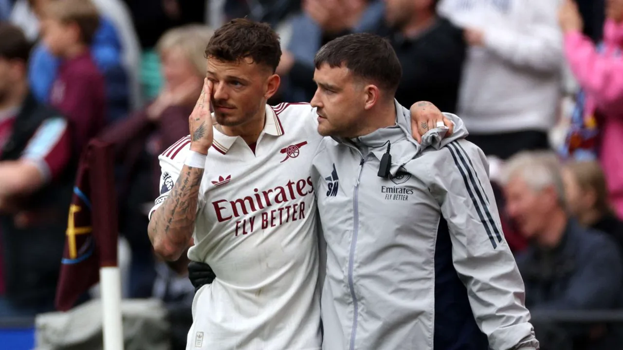 Ben White com a camisa do Arsenal sendo amparado após sofrer lesão no joelho durante partida