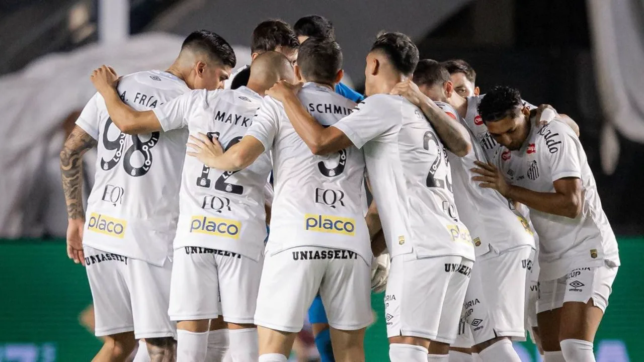 Jogadores do Santos em campo durante partida oficial, com expressão de tensão no vestiário ao fundo