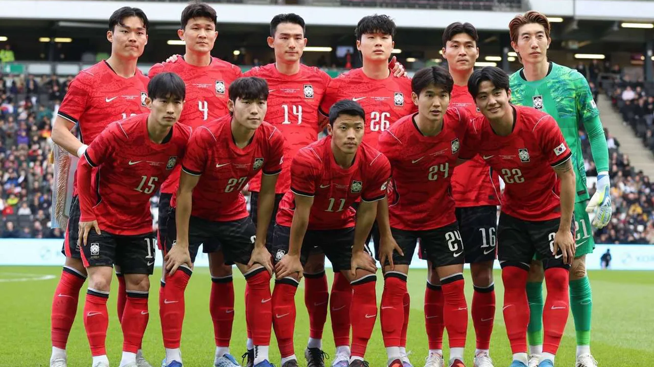 Son Heung-min com a camisa da Coreia do Sul erguendo o braço em comemoração durante partida eliminatória