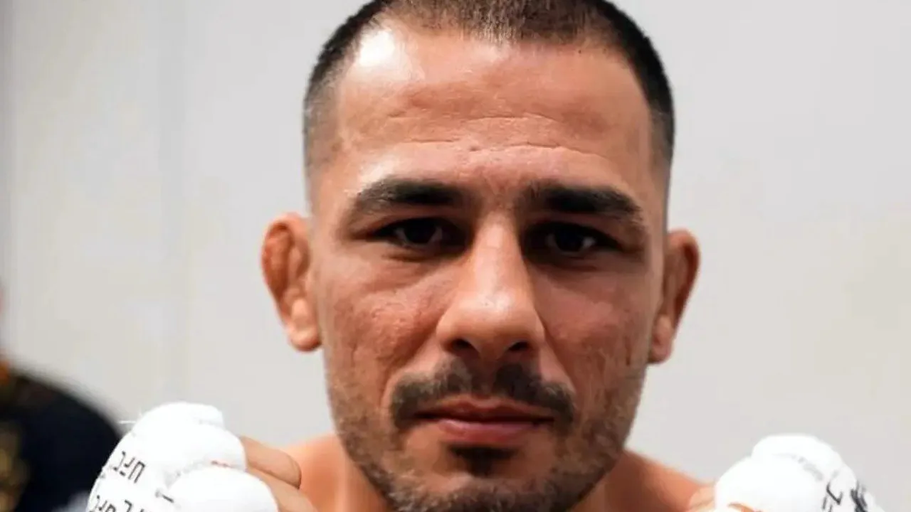 Alex Poatan com cinturão do UFC meio-pesado, olhando para cima em postura desafiadora no octógono