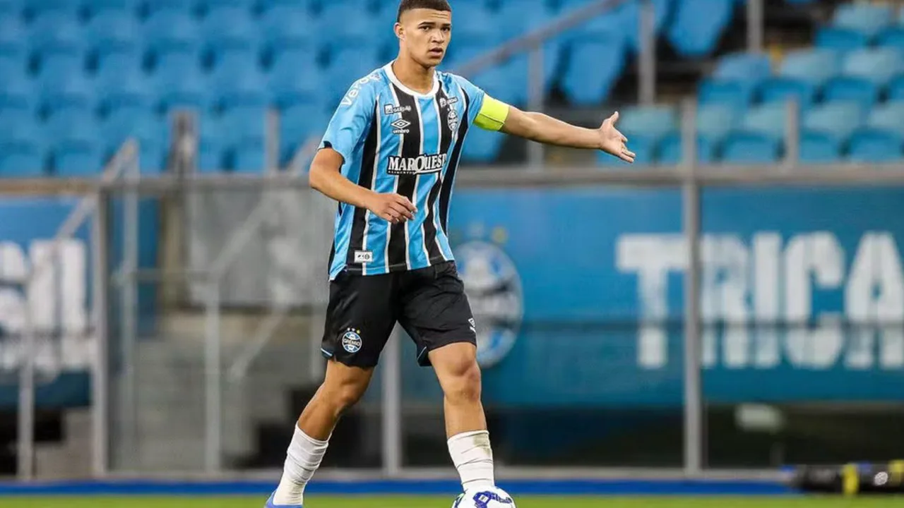 Zagueiro jovem do Grêmio em treino no CT, com uniforme tricolor, preparando-se para a partida contra o Bahia