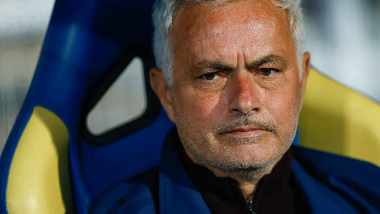 José Mourinho na beira do campo com o escudo do Benfica, olhando pensativo para o gramado