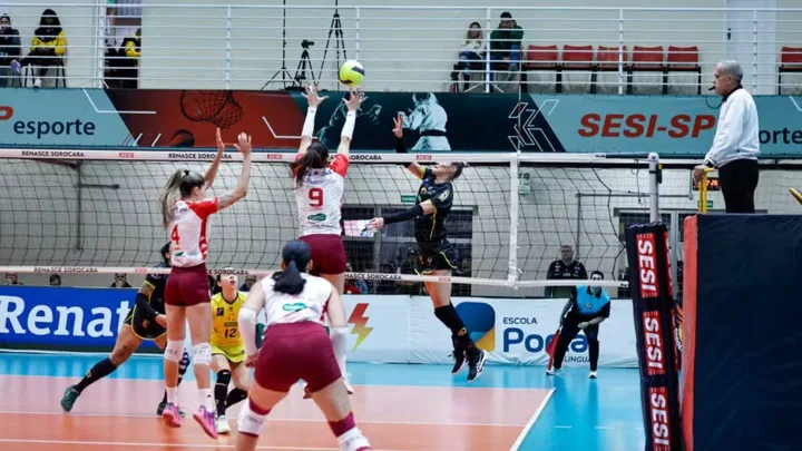 Jogador de vôlei em suspensão executando saque viagem durante partida internacional