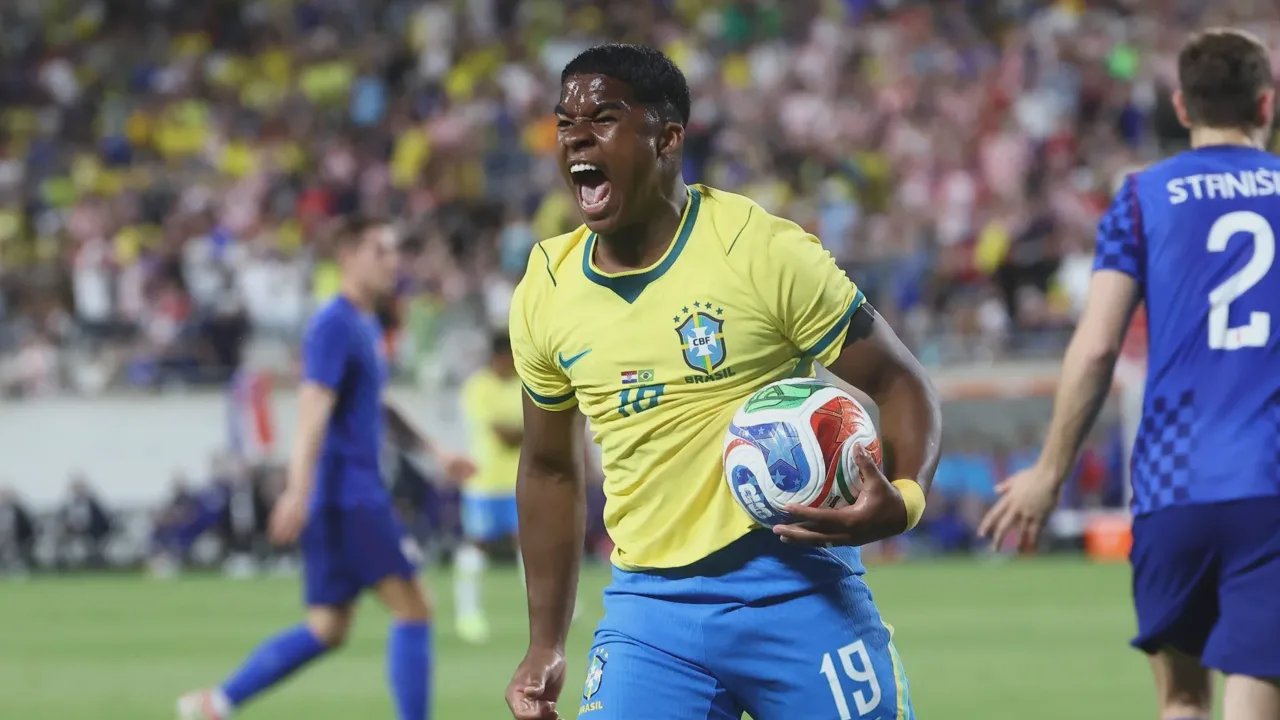 Endrick com a camisa da Seleção Brasileira comemorando gol em amistoso, braços abertos
