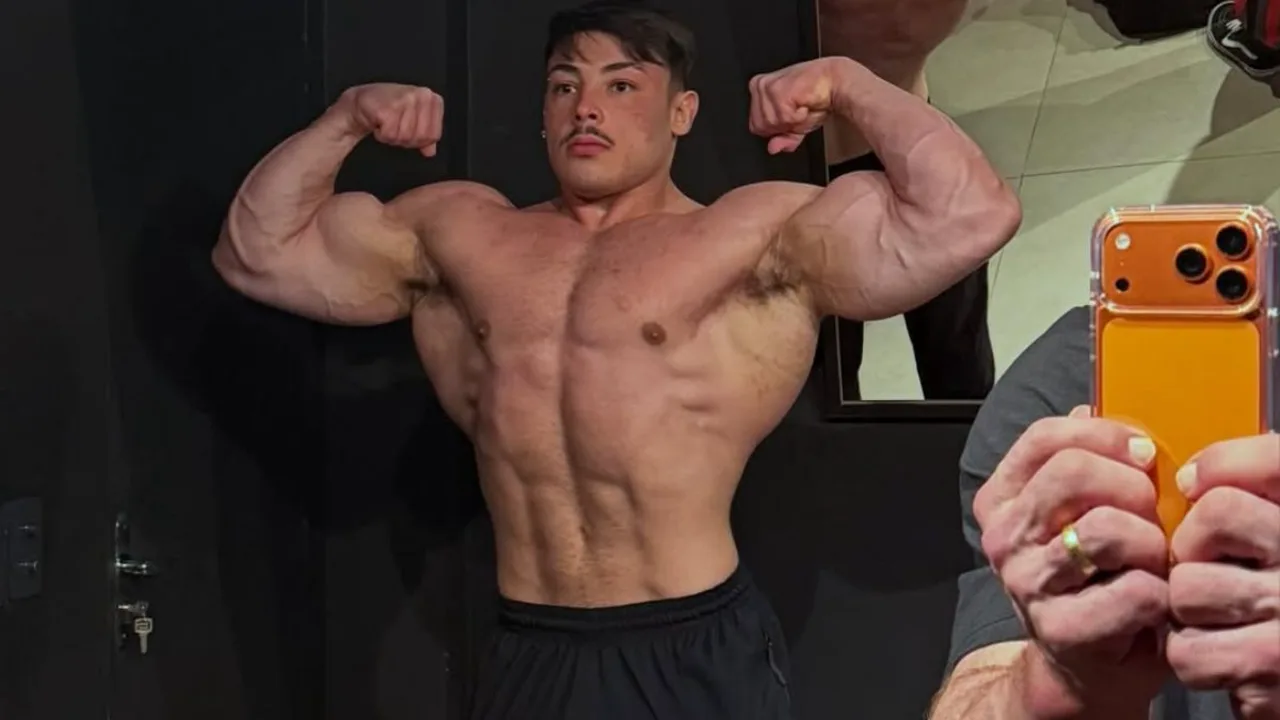 Fisiculturista jovem em preparação para competição, músculos definidos, academia com iluminação dramática