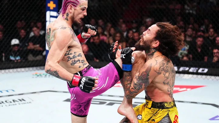 Lutador de MMA batendo com a mão aberta no tatame do octógono em sinal de rendição durante combate no UFC