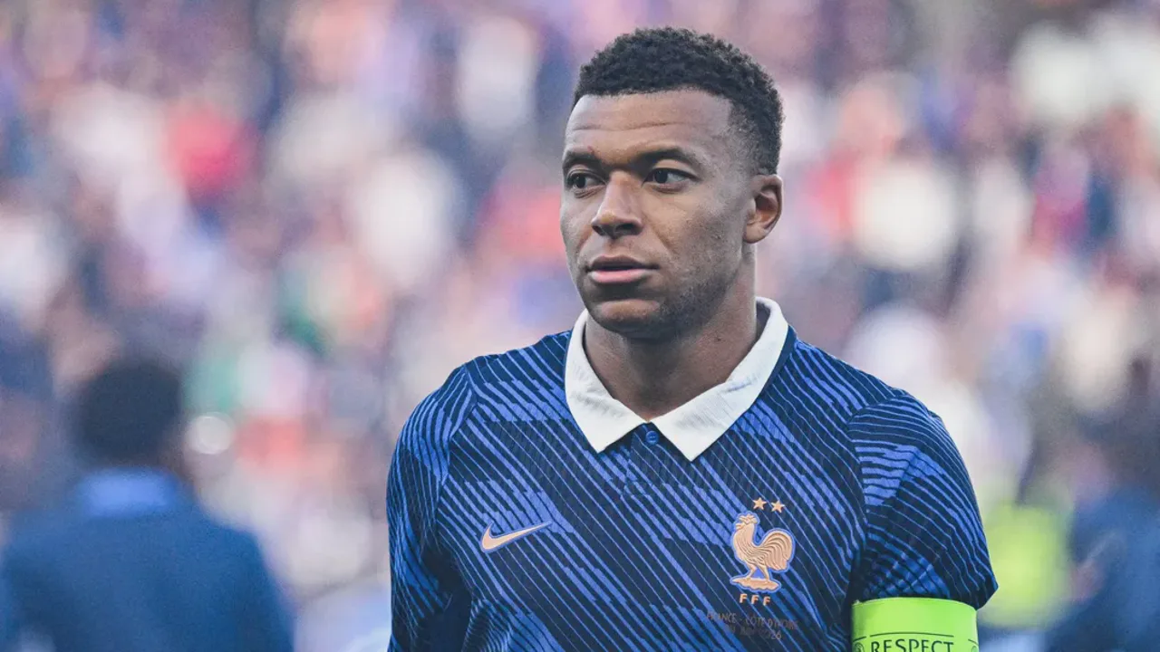 Kylian Mbappé em treino da seleção francesa com companheiros ao fundo, semblante sério