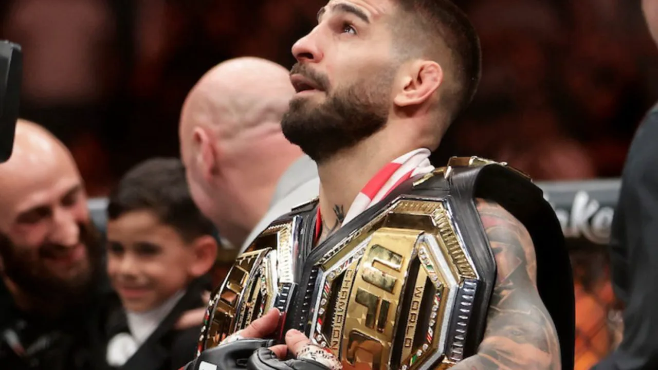 Alex Poatan em posição de guarda no octógono do UFC, com cinturão dos meio-pesados ao fundo