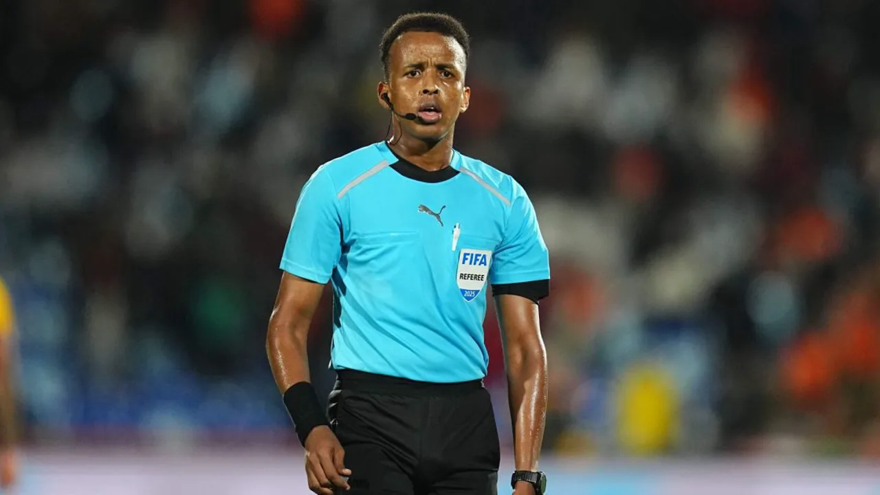 Árbitro Omar Artan em campo durante partida oficial da CAF, uniformizado, com apito na mão