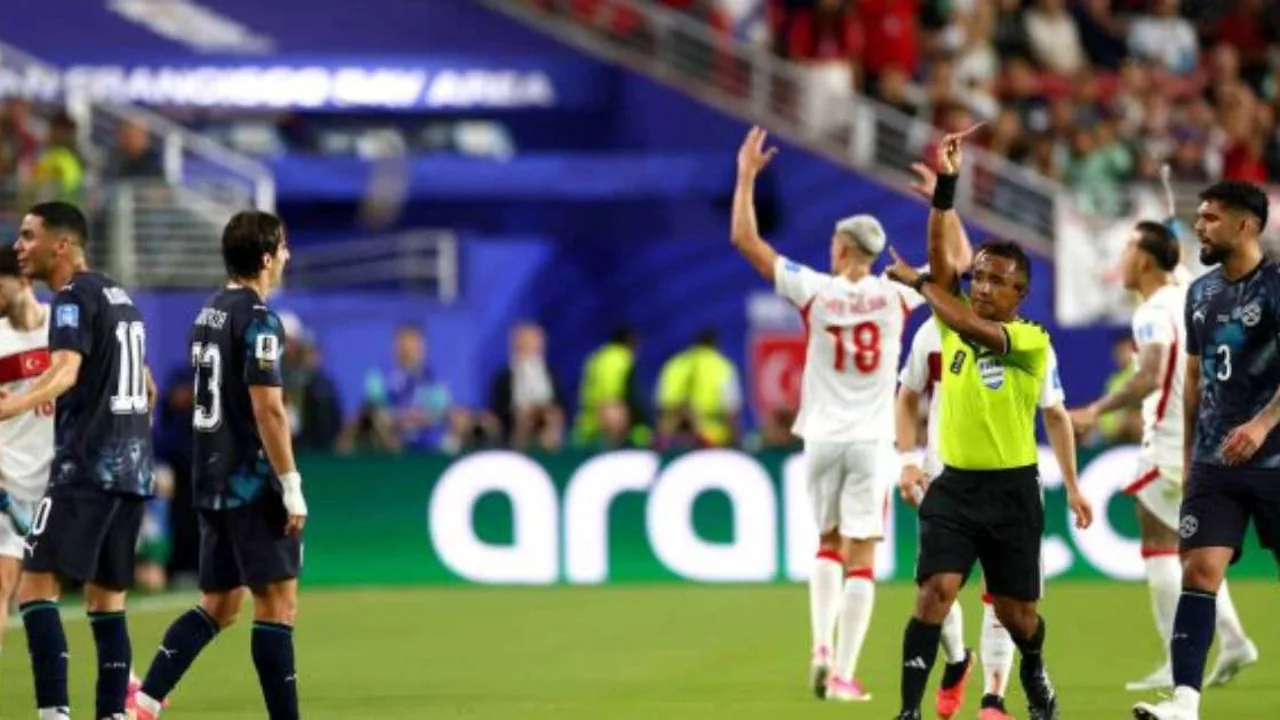 Goleiro em posição de defesa durante cobrança de pênalti na Copa do Mundo, com árbitro ao fundo segurando moeda