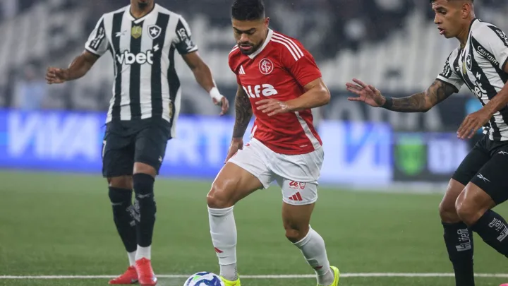 Técnico de futebol gesticulando na beira do campo enquanto jogador substituto se prepara para entrar