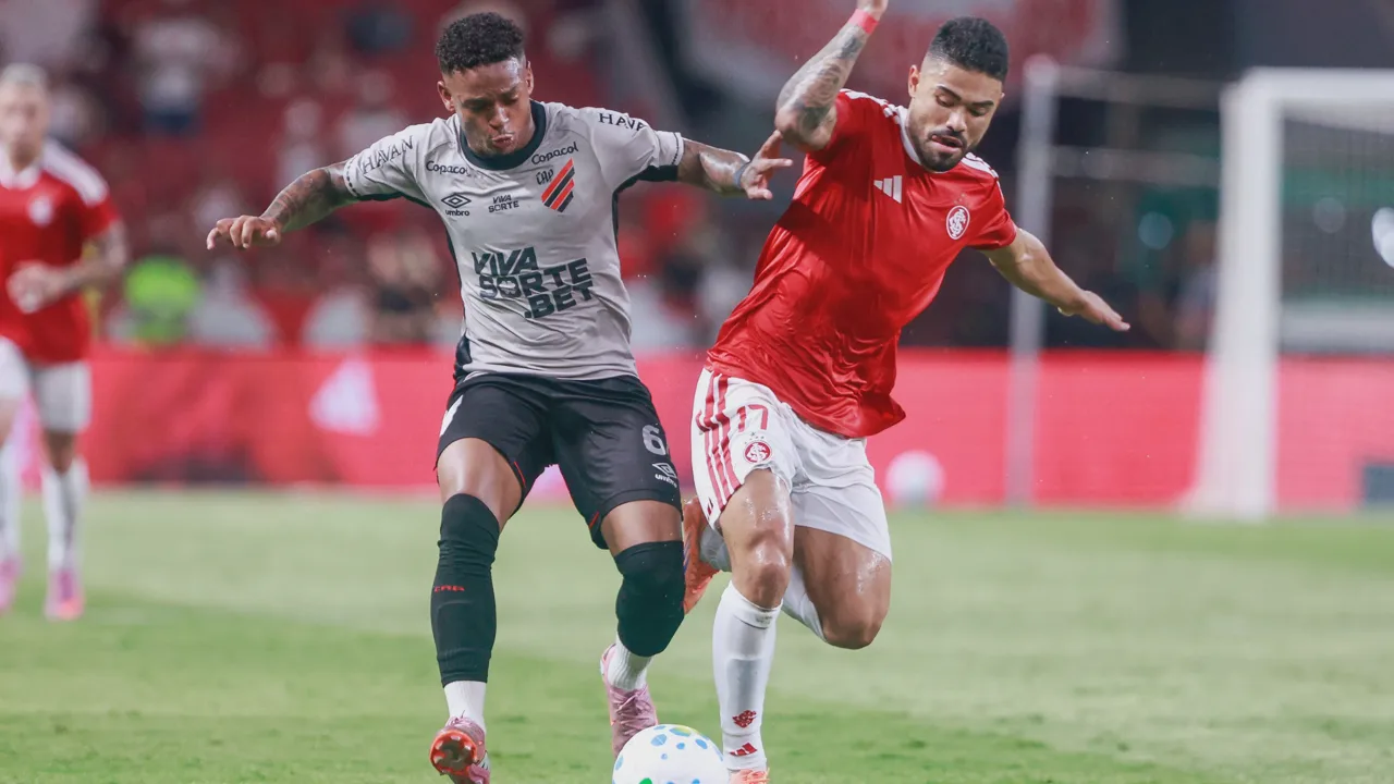 Árbitro de futebol gesticulando para o monitor do VAR à beira do campo durante uma partida profissional
