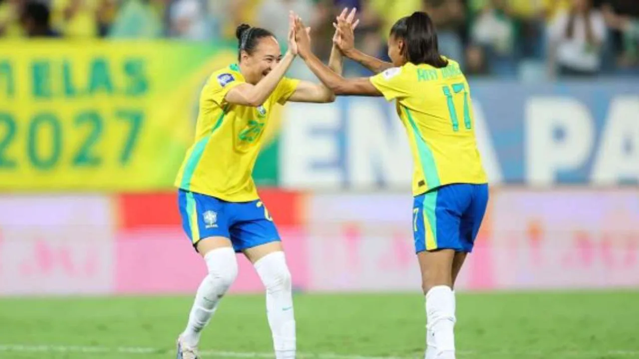 Jogadoras da Seleção Brasileira Feminina comemorando classificação com a bandeira do Brasil em estádio lotado